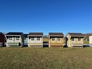 Row of Old Hickory Chicken Coops with nesting boxes and metal roofs displayed on sales lot, durable backyard buildings