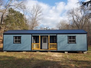 Old Hickory Utility Center Porch shed with metal roof in wooded backyard, portable backyard storage building for workshop, office, or studio use