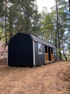 Old Hickory Lofted Center Porch shed with metal roof in wooded setting, portable backyard storage building for office or storage use