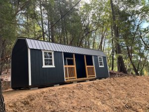Old Hickory Lofted Center Porch with metal roof in wooded hillside setting, portable backyard storage building ideal for studio or workshop use