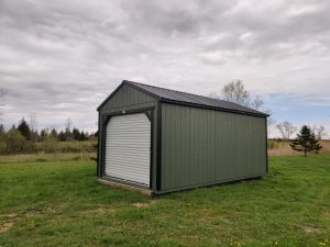 Old Hickory Utility Shed with Garage package with metal roof and roll-up door on grassy landscape with wildflowers