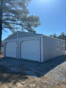 Old Hickory Double Wide Utility Shed with roll-up garage doors, white trim, metal roof and windows on sales lot