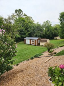 Old Hickory Side Utility Shed with Garage package, roll-up door and double barn doors in landscaped backyard