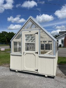 Old Hickory Greenhouse with clear panels and Navajo wainscot on sales lot, ideal for year-round gardening