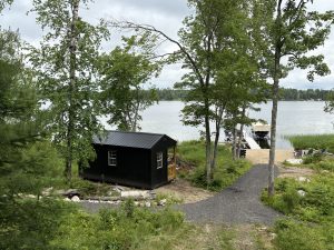 Old Hickory Utility Shed with Side Porch, windows and metal roof, outdoor storage shed in wooded lakeside landscape