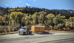 Old Hickory Utility Shed with T1-11 Siding and metal roof, outdoor storage building delivered on trailer in forested hills
