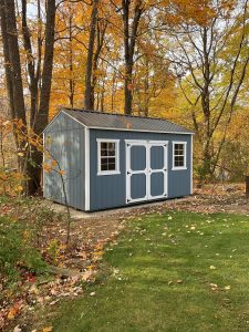 Old Hickory Side Utility outdoor storage shed in Smoky Blue with metal roof and double barn doors in wooded fall backyard