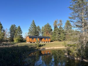 Old Hickory Lofted Center Porch with metal roof and 9-lite door overlooking pond and forest landscape, ideal for office, workshop or storage use