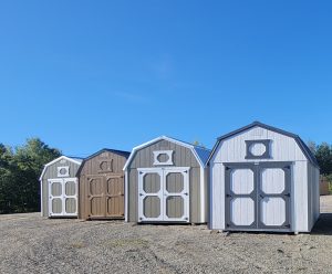 Row of Old Hickory Lofted Barns on sales lot, portable backyard buildings with metal roofs and double doors