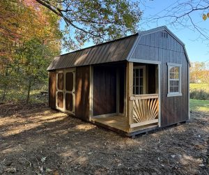 Old Hickory Lofted Barn with Side Porch, metal roof and double barn doors, durable backyard storage building on wooded autumn property