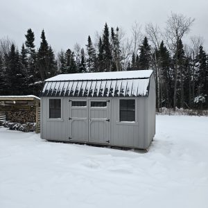 Old Hickory Side Lofted Barn with metal roof, windows and double barn doors, portable backyard storage building in snowy winter yard