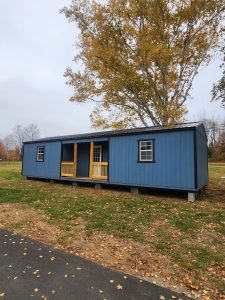 Old Hickory Utility Center Porch with metal roof and covered porch in scenic autumn rural yard, portable storage building for office or workshop use