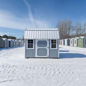 Old Hickory Lofted Barn with metal roof, windows and single barn door, backyard storage building on sales lot in front of rows of Utility Sheds