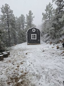 Old Hickory Lofted Barn with metal roof and octagonal window, portable backyard building in snowy mountain landscape